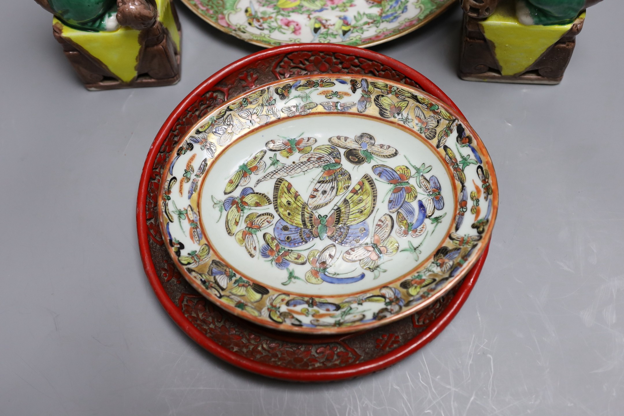 A Cantonese famille rose plate and teapot with cover, a pair of Chinese seated dogs, and a tureen with cover and oval dish, And a Chinese faux lacquer dragon and Phoenix dish, teapot 18 cms high